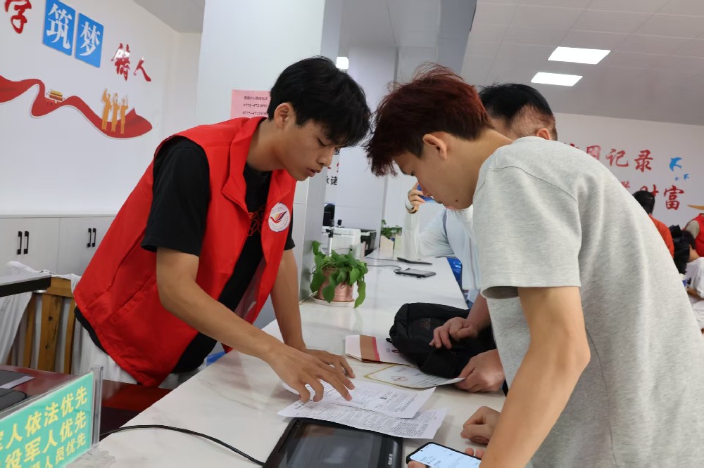 覃塘区：志愿者指引前来办理贷款业务的学生.jpg